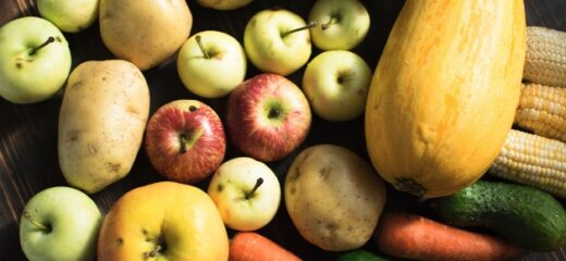 An image shows some fruits and vegetables placed on a wooden surface.