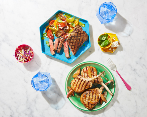 The image shows two plates, one with roasted chicken & other with a combination of vegetables & chicken, accompanied by two water glasses.