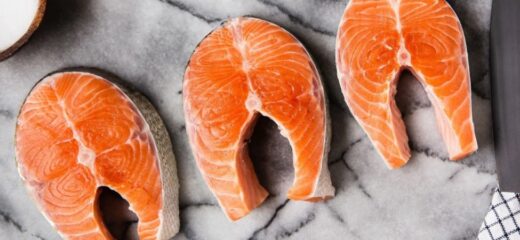 A picture of sustainable bluefish salmon steaks placed on a marble surface with a knife placed in the side.