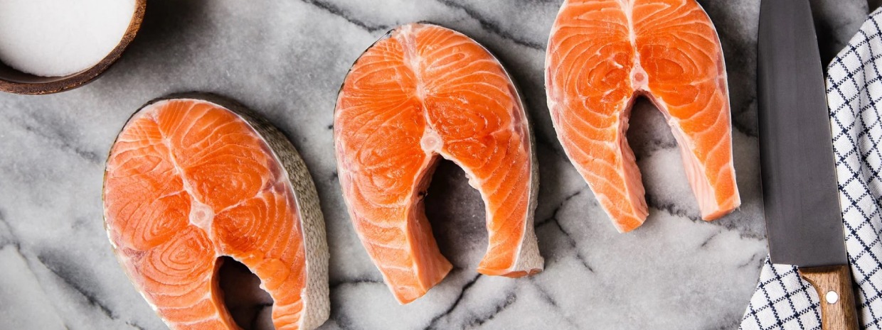 3 salmon steaks on marble cutting board.