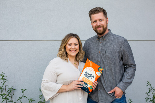 A picture of a couple standing together to get a picture clicked while holding humble potato chips in their hand.