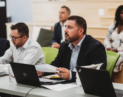 A picture of persons judging the Plastic Waste Challenge competition while holding paper in their hand and a laptop placed on the table.