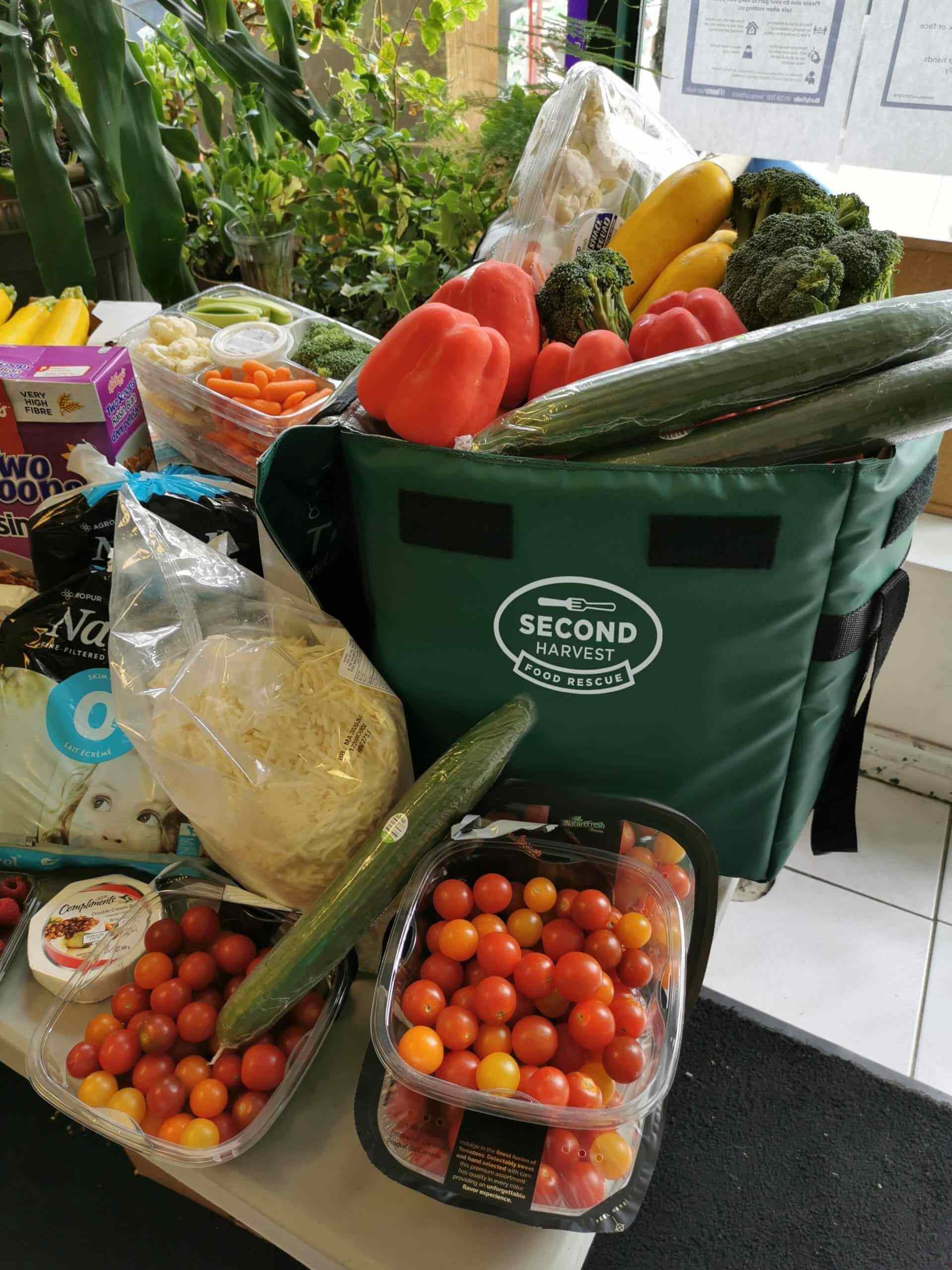 This image shows fresh vegetables on the table and vegetables in the Second Harvest Food Rescue Cooler's bag.